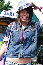 Standing on front of taxi adjusting her hat wearing denim jacket